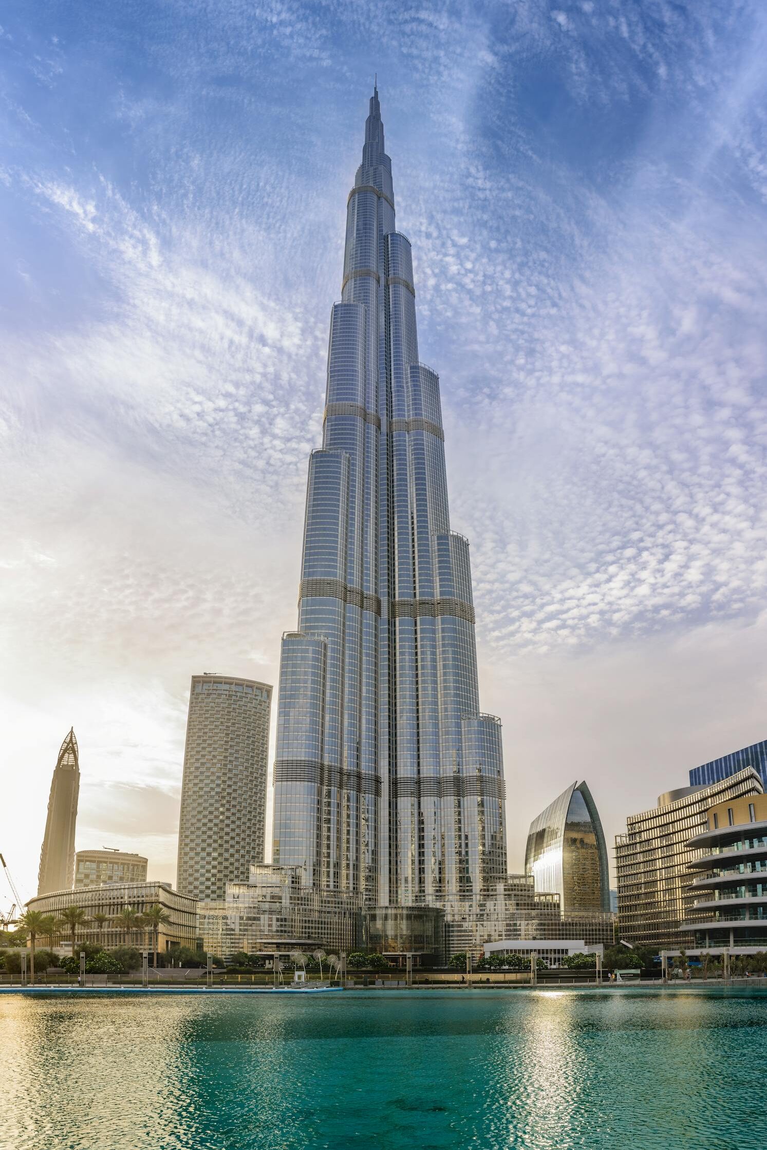 Majestic Burj Khalifa against a bright blue sky reflecting in water, Dubai.
